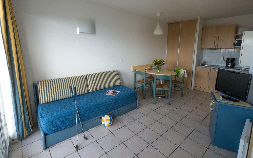 Slide Living area with sofa bed and fully equipped open kitchen in a studio at the Eugénie residence in Biarritz