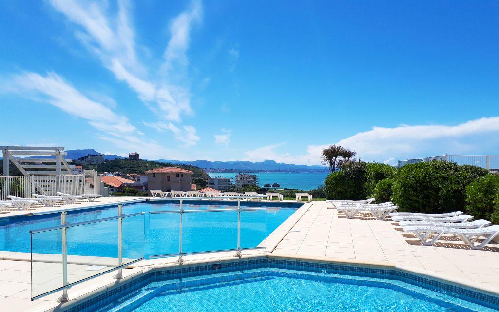 Slide View of the two outdoor pool areas at the Eugénie residence in Biarritz, with sun loungers and sea views