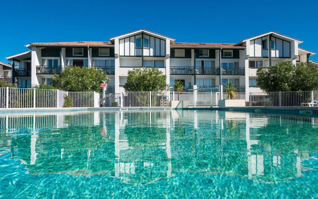 Slide View of the outdoor pool and the Ilbarritz residence in Bidart under a blue sky