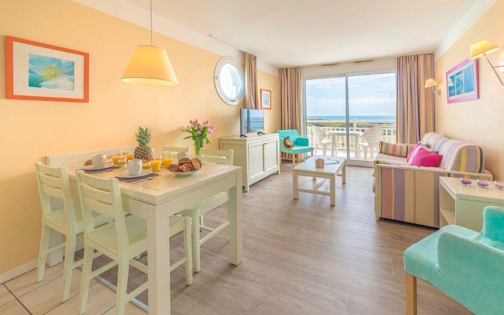 Slide Pièce à vivre aménagée avec télévision et canapé-lit donnant sur un balcon privatif avec vue mer à la résidence l'Estran aux Sables-d'Olonne