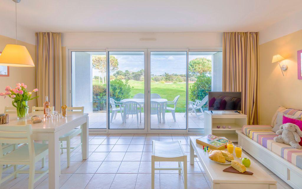 Slide Spacious, fully equipped living room with television and sofa bed opening onto a private outdoor area overlooking the residence’s gardens at the L’Estran residence in Les Sables-d’Olonne