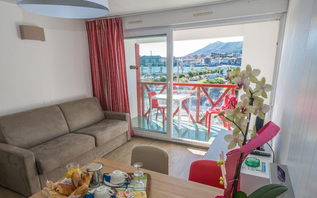 Slide Salon avec canapé lit et balcon vue sur le port d’un logement de la résidence Sokoburu à Hendaye