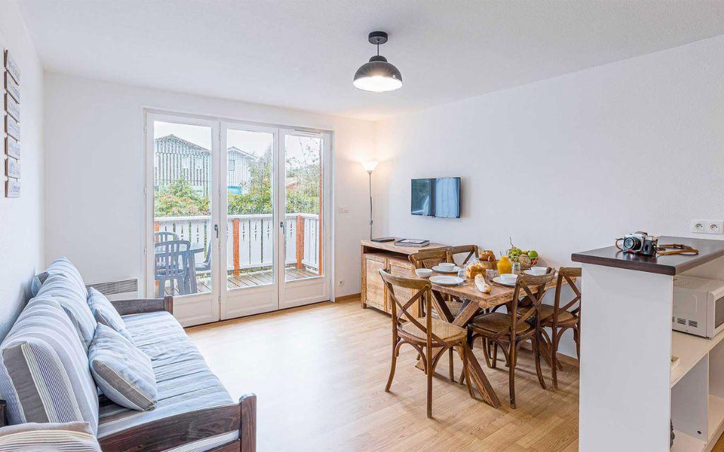 Slide Salon équipé d'une télévision ouvert sur un espace extérieur d'un appartement aux Rives Marines au Teich