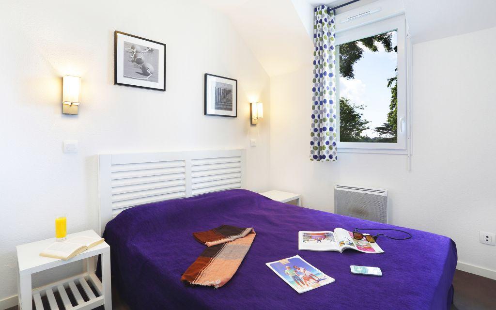 Slide Chambre avec un lit double et tables de chevets au sein d’une maisonnette du Domaine de la Baie