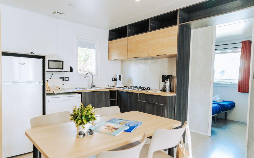 Slide Cuisine ouverte sur l’espace repas dans un cottage premium du camping les places dorées*****