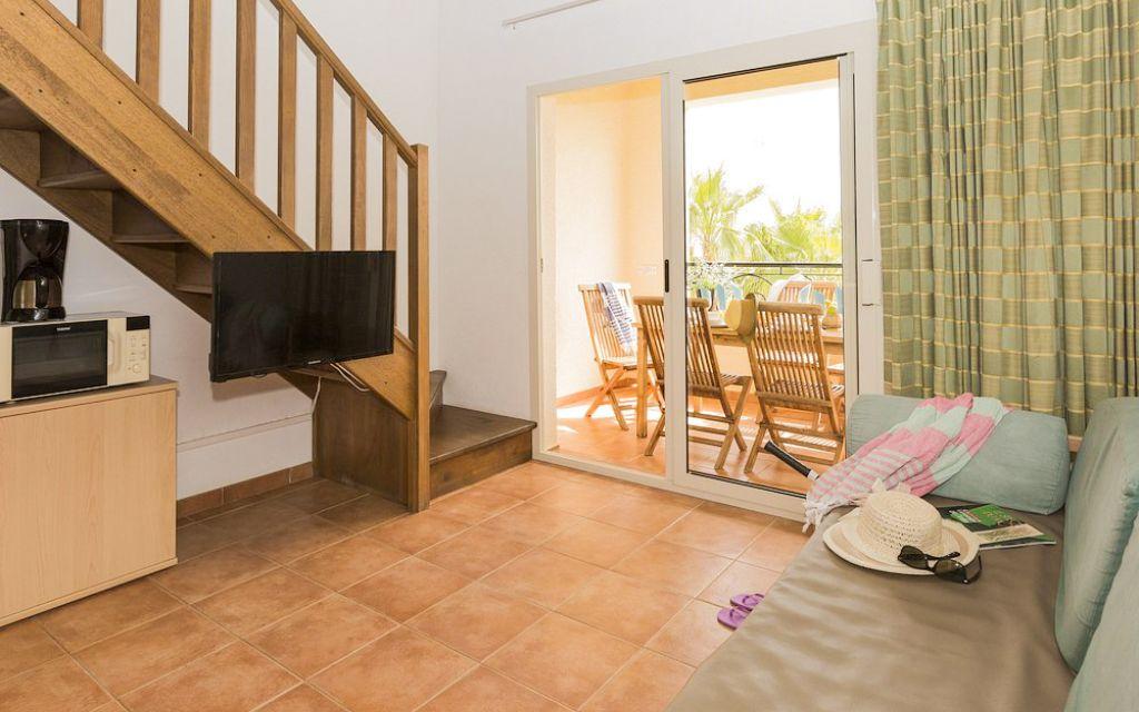 Slide Living room with television opening onto the balcony and access to the mezzanine in the apartments of the Sognu di Mare residence in Linguizzetta
