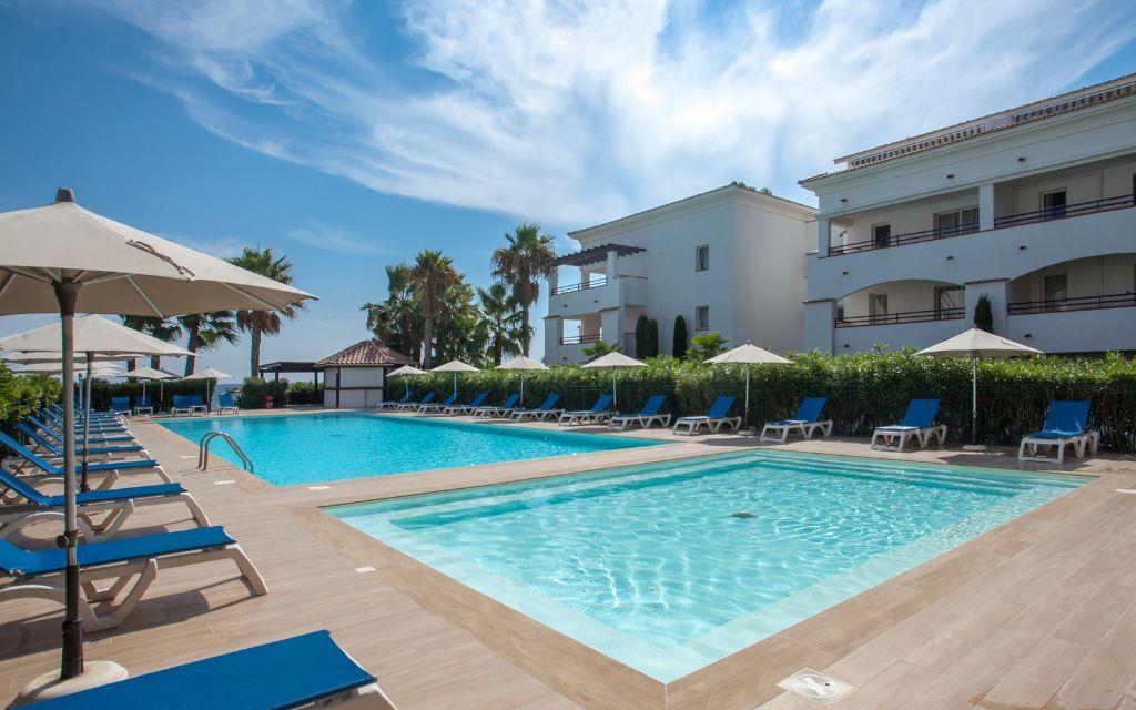 Slide Central outdoor swimming pool and paddling pool with sun loungers at the Sognu Di Rena residence in Moriani-Plage
