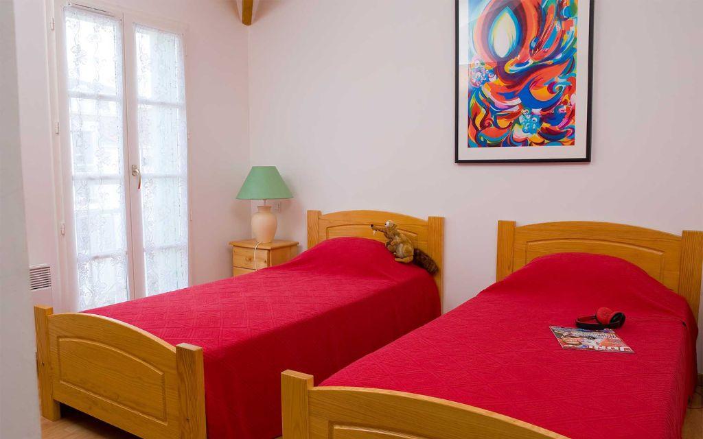 Slide Bedroom with two single beds and a bedside table in a Fontenelles house