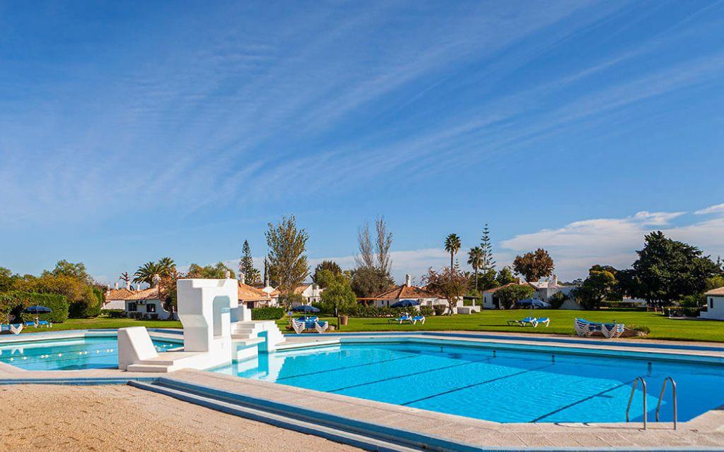 Slide Unheated outdoor swimming pool of the Pedras del Rei residence with green space and sun loungers in the background