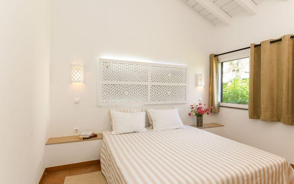Slide Bedroom with a double bed for two people and a window overlooking the gardens of the Pedras del Rei residence