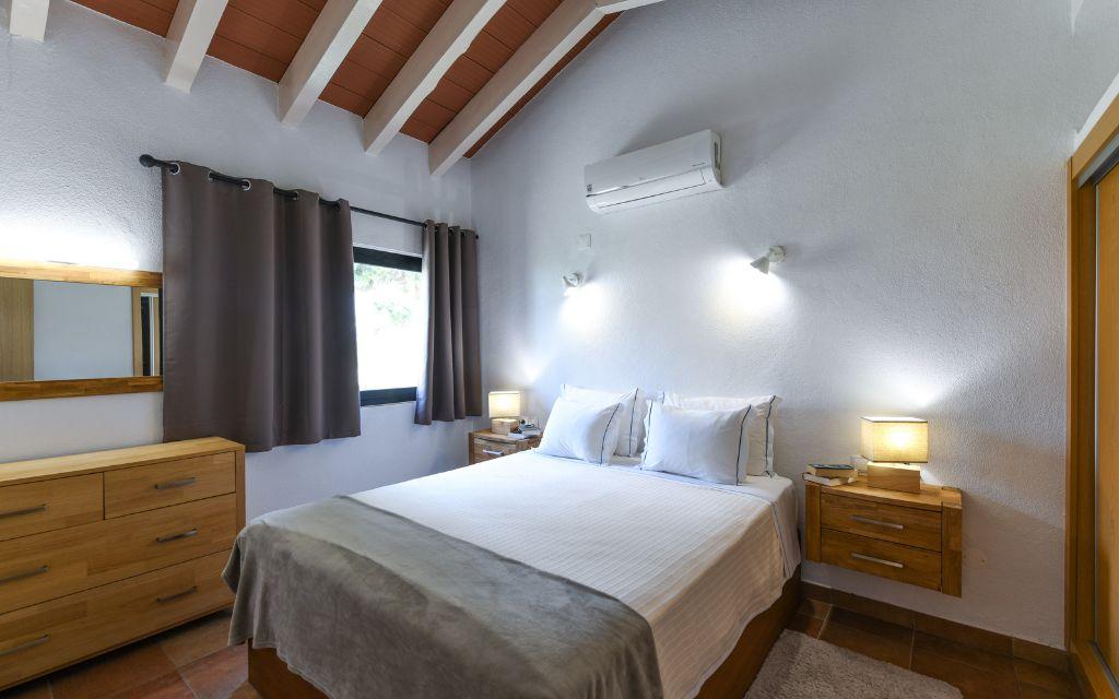 Slide Chambre avec un lit double, table de chevet et commode au sein d’une villa à Pedras da Rainha