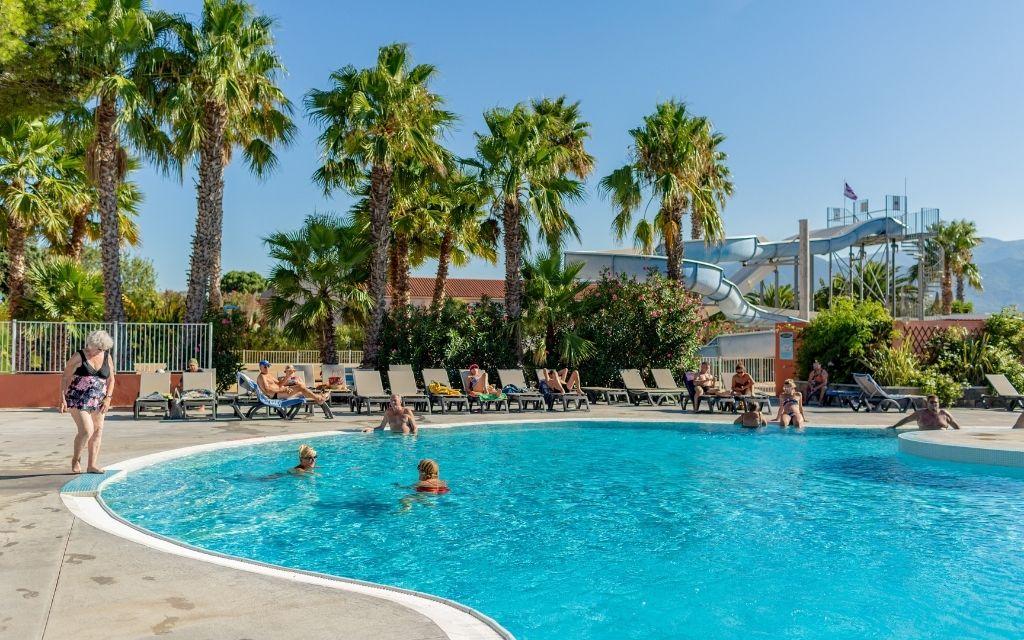 Slide Outdoor swimming pool with sun loungers, slides and palm trees at Résidence Antinéa