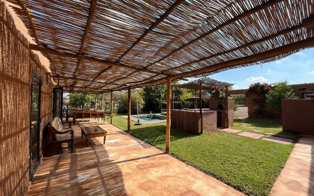 Slide Large shaded terrace with outdoor furniture, opening onto the enclosed garden at Villa Dar Wellness