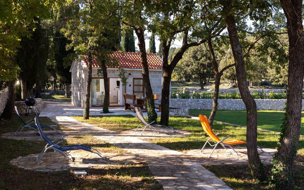 Slide Outdoor area of the Sveta Ana Lodges cottages set in a park, with sun loungers and the option to rent a barbecue