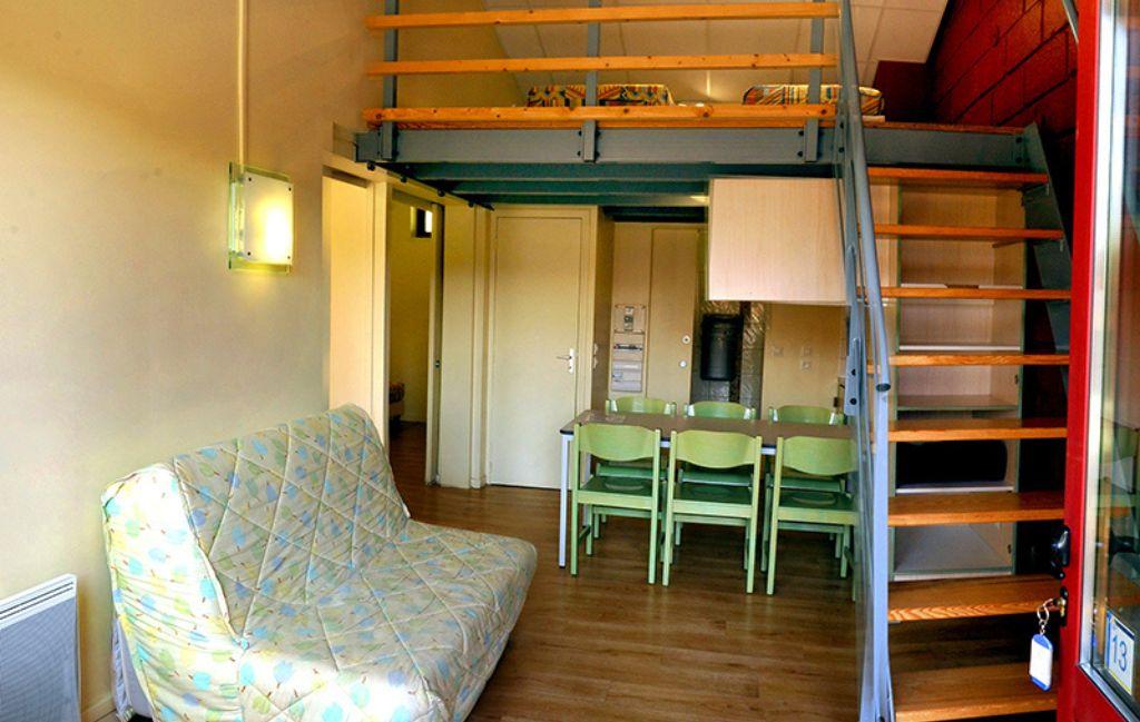 Slide Séjour d’un gîte de la résidence Vorey-sur-Arzon  avec canapé-lit, cuisine ouverte et duplex