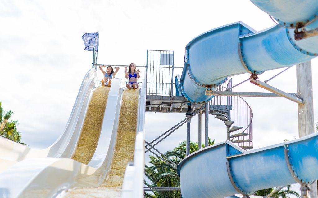 Slide Outdoor swimming pool with sun loungers, slides and palm trees at Résidence Antinéa