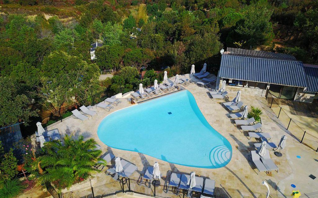 Slide Piscine à débordement en forme de coeur avec chaises longues et parasols et vue sur la mer au camping Lacasa à Calcatoggio