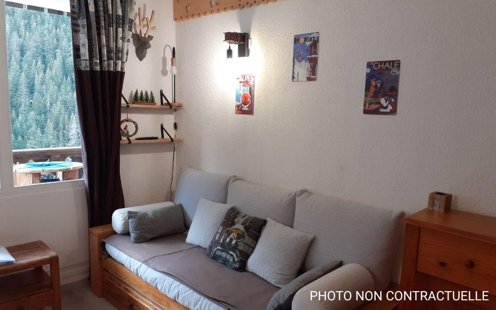 Slide Salon avec canapé-lit à la décoration épurée avec ouverture sur un balcon dans les studios a Valfrejus