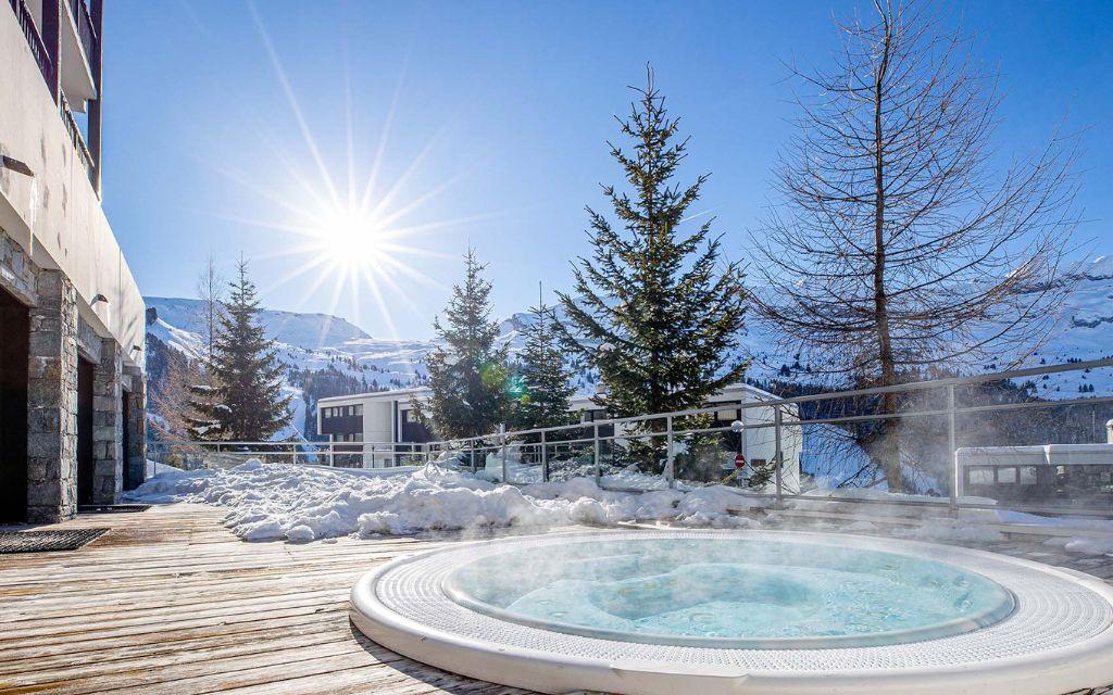 Slide Espace bien-être en extérieur avec jacuzzi face aux montagnes de Flaine à la résidence Les Terrasses de Veret