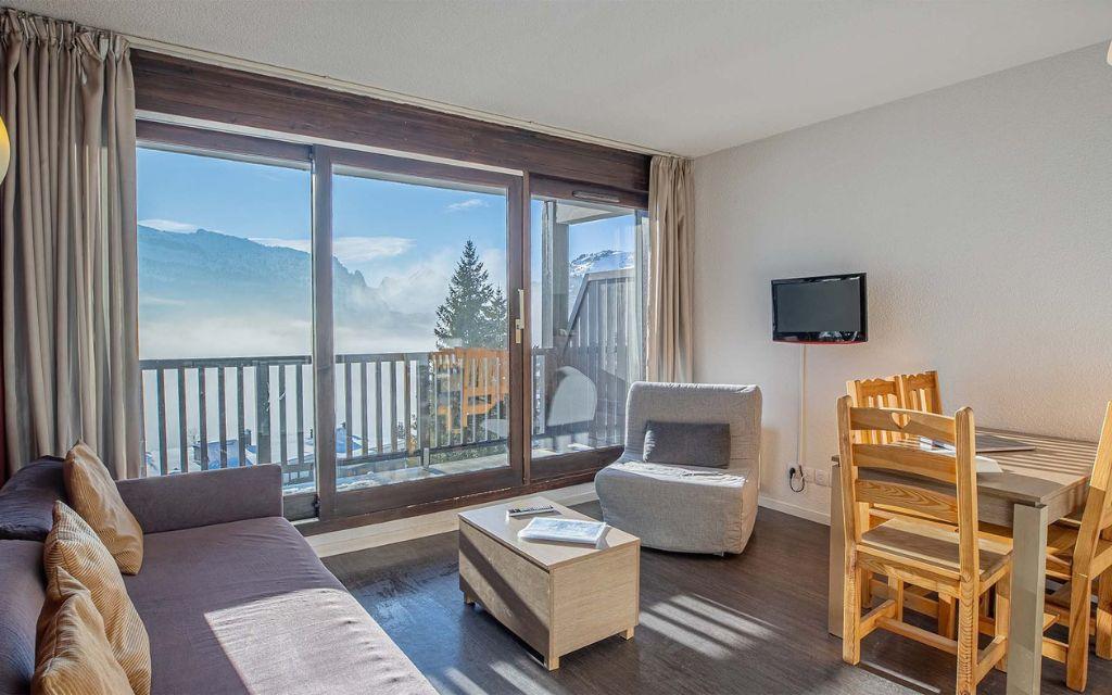 Slide Living area with a chair bed and dining area in the apartments at Les Terrasses de Veret Residence in Flaine