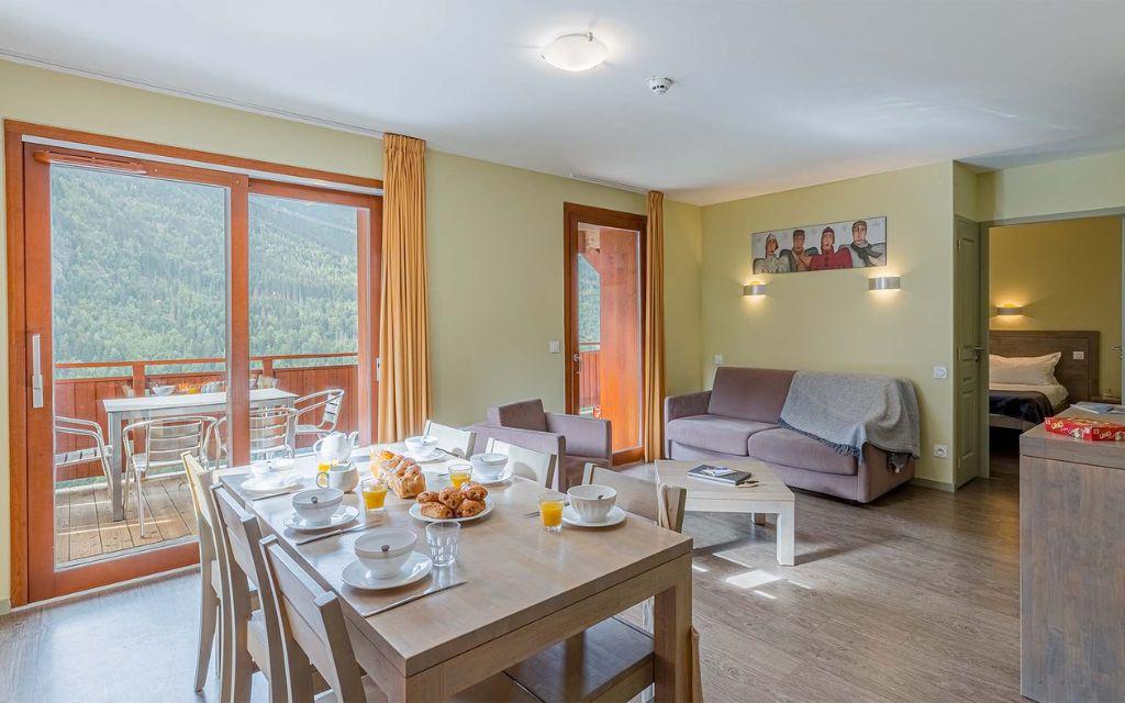 Slide Dining area opening onto a balcony with mountain views in the apartments at Les Épinettes Residence in Vaujany