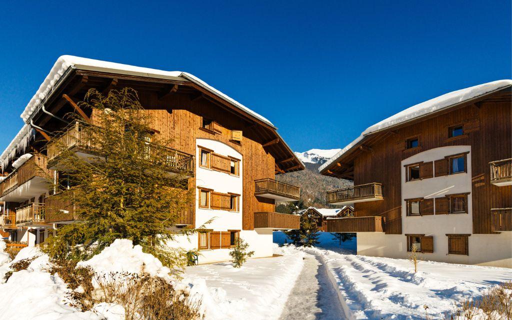 Slide Exterior view of Les Fermes de Samoens residence with sunshine and snow