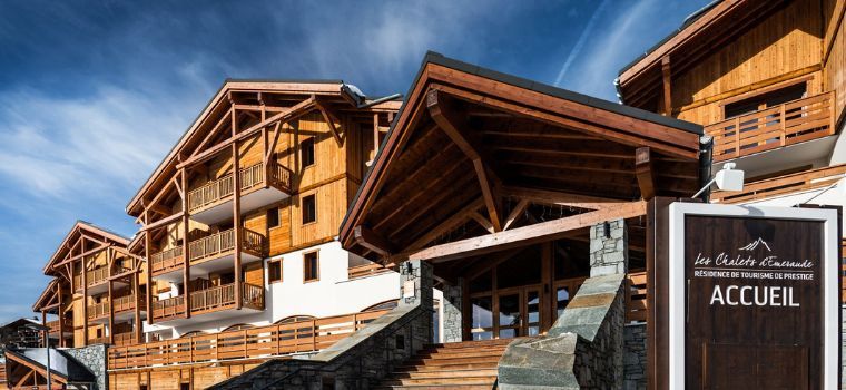 Wooden exterior façade of the Les Chalets d’Émeraude residence in Les Saisies under the sun