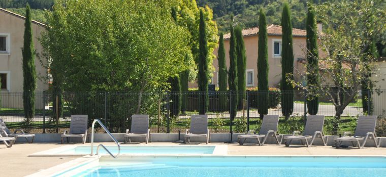 Swimming pool with deck chairs at the Hameau des Sources residence in Montbrun heritage-listed village