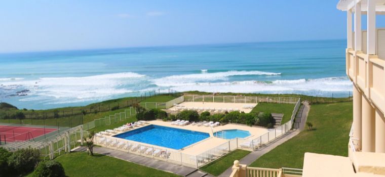 Overall view of the outdoor areas of the Eugénie residence in Biarritz, featuring an outdoor pool and a tennis court