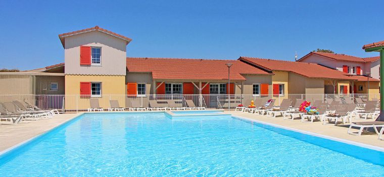 Heated outdoor swimming pool surrounded by sun loungers and the holiday cottages of La Grenadine residence