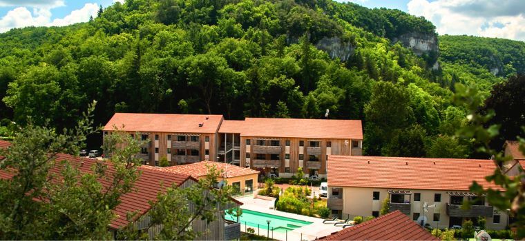 Aerial view of Résidence Le Clos du Rocher with greenery all around and an outdoor pool at its center