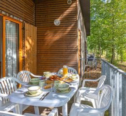 Terrasse aménagée d’un cottage en bois au Valjoly avec table dressée pour le petit-déjeuner en pleine nature