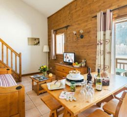 Salon chaleureux avec escalier en bois et coin cuisine aux Fermes de Samoëns en Haute Savoie
