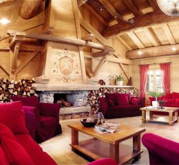 Salon chaleureux avec cheminée et canapés confortables à la résidence Le Hameau du Beaufortain aux Saisies
