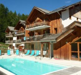Overview of La Combe d'Or residence in Les Orres 1800 under the sun with swimming pool