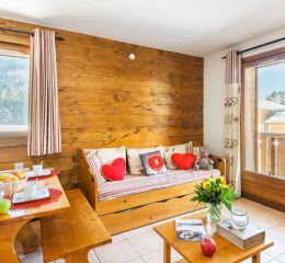 Living room with sofa bed and mountain views in an apartment in the Les Fermes de Samoens residence