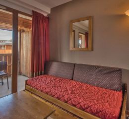 Salon avec canapé-lit et fenêtre qui donne sur le balcon avec la vue montagne