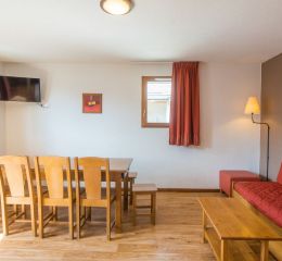 Living room with television, table for a large family and sofa in the Les Etoiles d'Orion residence