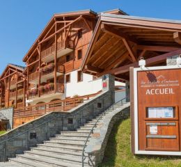 Front view of the Les Chalets d’Émeraude residence in Les Saisies under the sun