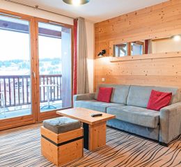 Living room with sofa bed and balcony overlooking the mountains at Les Chalets d’Émeraude