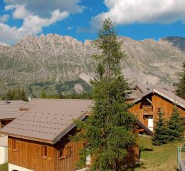 Overall view of the Résidence L’Orée des Pistes in summer with mountain views