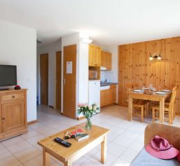 Living room with open kitchen and lounge area with TV at the Résidence L’Orée des Pistes