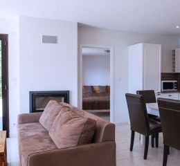 Vue d’ensemble du séjour avec canapé et table à manger des appartements au domaine l’Écrin du lac à Chorges
