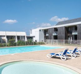 Piscine extérieure avec pataugeoire et transats au sein de la résidence Fleur de Sel