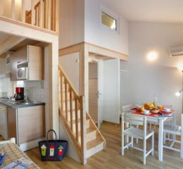 Séjour ouvert sur une cuisine équipée avec TV dans les maisonnettes des Sabees Vignier à Oléron