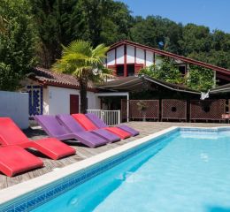 Piscine avec transats colorés au bord de la piscine de la résidence les collines iduki