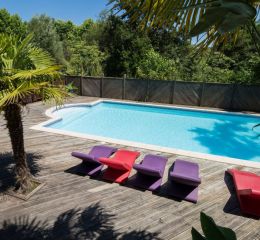 General view of the swimming pool with sun loungers and palm trees at the Les Collines Iduki residence