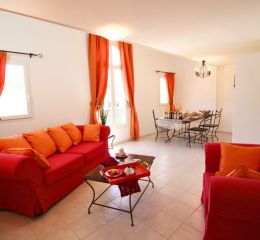 Salon avec canapé et table à manger en fond dans un appartement du Domaine de Bourgeac