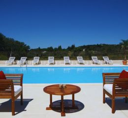 Outdoor swimming pool with sun loungers and garden furniture at the Bourgeac estate near Les Beaux de Provence