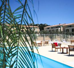 View of the outdoor swimming pool with garden furniture and buildings in the background at the Bourgeac estate